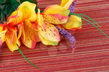Colorful artificial flowers on cloth background, closeup picture.
