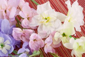 Colorful artificial flowers on cloth background, closeup picture.