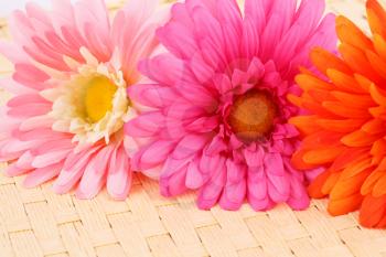 Colorful fabric daisies on bamboo background, closeup picture.