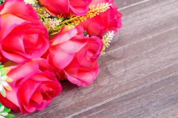 Red fabric roses on wooden background.