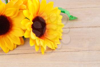 Yellow fabric daisies on wooden background.