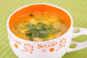 Vegetable soup in bowl on green bamboo background.