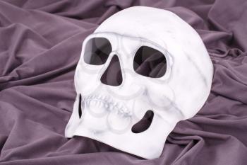 White skull mask on fabric background.