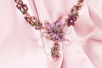 Stylish necklace on pink fabric background.