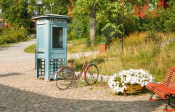 Old phone box and bicycle at Skansen, the first open-air museum and zoo, located on the island Djurgarden in Stockholm, Sweden. 