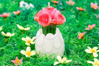 Easter egg with flower candle on articial grass background.