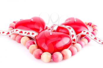 Red heart candles, wooden necklace and ribbon isolated on white background.