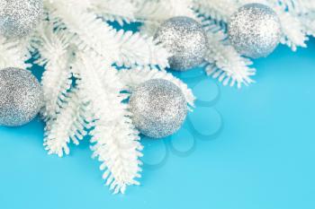 Christmas decoration with gray balls and fir-tree white branch on the blue background.
