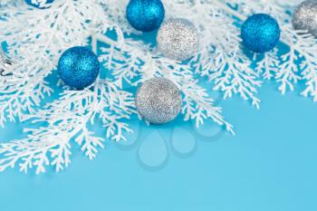 Christmas decoration with balls and white fir tree branch on blue background.