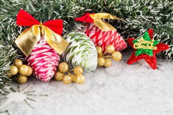 Christmas decoration with fir tree garland, cones and star on gray background.