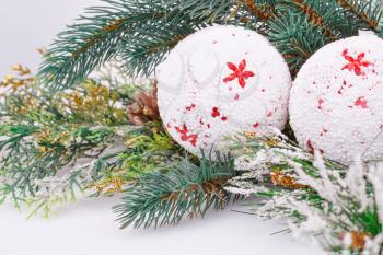 Christmas white balls, cones and fir-tree branch on gray background.