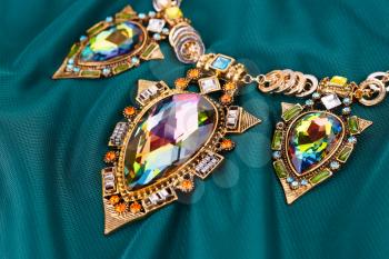 Stylish necklace with gemstones on fabric background.