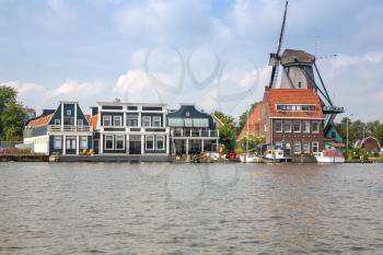 Traditional, authentic dutch windmill and houses at the river Zaam.