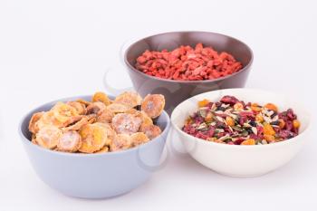 Dried fruits, berries and seeds in bowls on gray background.