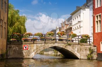 Old bridge with colorful flowers over the canal in the historical medieval city.