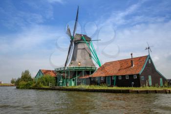 Traditional, authentic dutch windmill at the river Zaam in Zaanse Schans village.