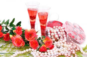 Two glasses, red roses, colorful pearls necklaces and gift box on white background.