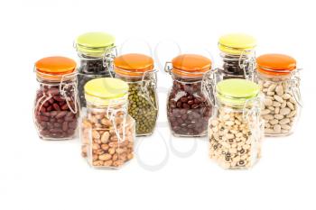 The collection of different beans in the glass jars isolated on a white background.