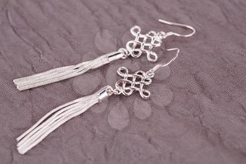 Silver earrings on fabric background.