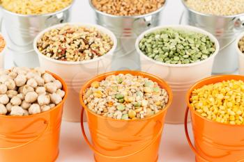 The collection of different groats in the metallic buckets. Quinoa, wheat, split peas, chickpea, and lentil.