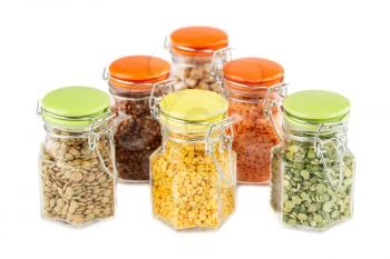 The collection of different groats in the glass jars isolated on white background. Split peas, buckwheat, chickpea and colorful lentils.