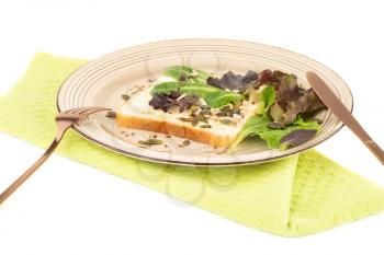Sandwiches with butter, seeds and lettuce on plate on green towel on white background.
