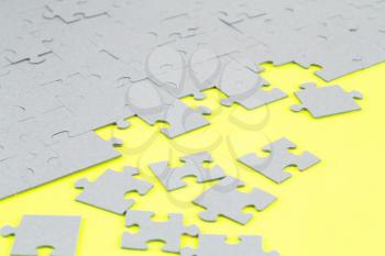 Unfinished jigsaw puzzle pieces on yellow background.