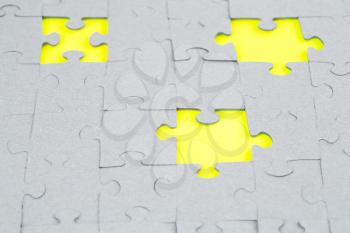 Unfinished jigsaw puzzle pieces on yellow background.