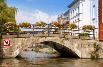 Old bridge with colorful flowers over the canal in the historical medieval city.