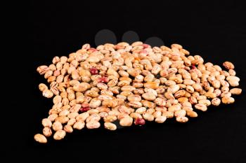 The heap of borlotti beans isolated on a black background.