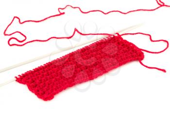 Red yarn with knitting needles on white background.