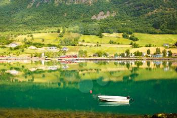 Landscape with mountains, village, white boat and fjord in Norway.