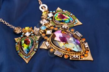 Stylish necklace with gemstones on fabric background.