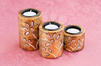 Three brown ancient style candle nests on cloth background.