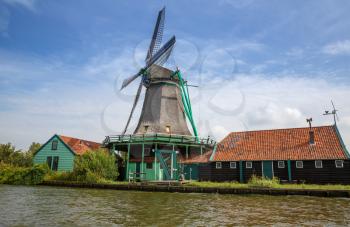 Traditional, authentic dutch windmill at the river Zaam in Zaanse Schans village.