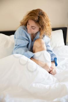 Woman in blue sweater sitting in the bed.