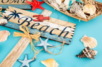 Wooden signs welcome beach and shells on blue background.