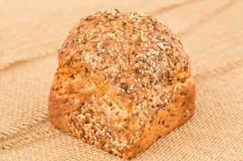 Wholegrain bread bun with oat  on the burlap background.