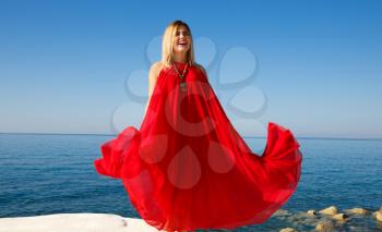 Woman in the red dress on the white stone at the beach in Cyprus.