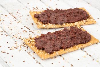 Sandwiches with olive paste on gray wooden background.