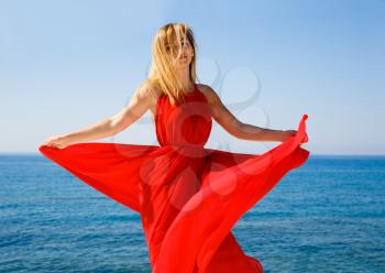 Pretty blond woman in the red dress at the beach in Cyprus.