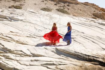 Blond women in the long dresses on the white rock in Cyprus.