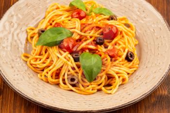 Pasta spaghetti Napoli or Napolitana on plate on brown wooden background. Italian cuisine.