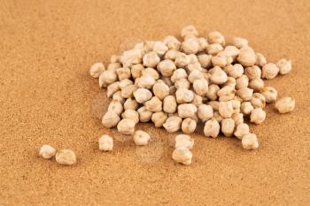 The pile of raw chickpeas on the brown background.
