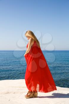 Pretty blond woman in the red dress at the beach in Cyprus.