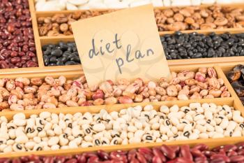 Different beans in the wooden box with the notes  diet plan on paper. Borlotti, adzuki, black turtle, black eyed beans.