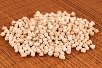 The pile of raw chickpeas on the brown bamboo background.