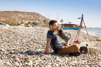 The man with dogs and tripod on the beach.