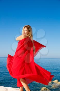 Blond woman in the red dress at the beach in Cyprus.