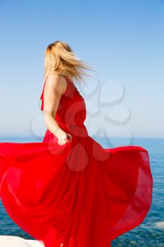 Blond woman in the red dress at the beach in Cyprus.